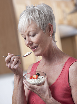 Woman eating cottage cheese and fruit.
