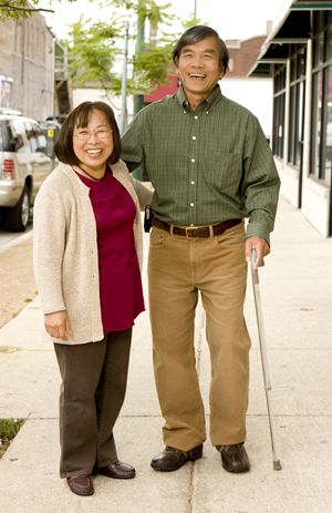 Hombre con bastón caminando por una calle de ciudad con una mujer.
