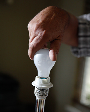 Primer plano de las manos de un hombre que está colocando una bombilla en una lámpara.