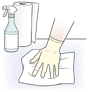 Mano con guante limpiando una superficie con una toalla de papel.
