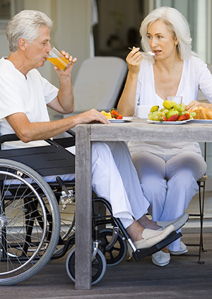 Mujer y hombre en silla de ruedas desayunando.