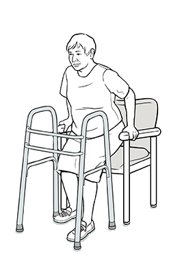 Mujer bajando hacia una silla mientras mantiene la pierna operada un poco hacia adelante.